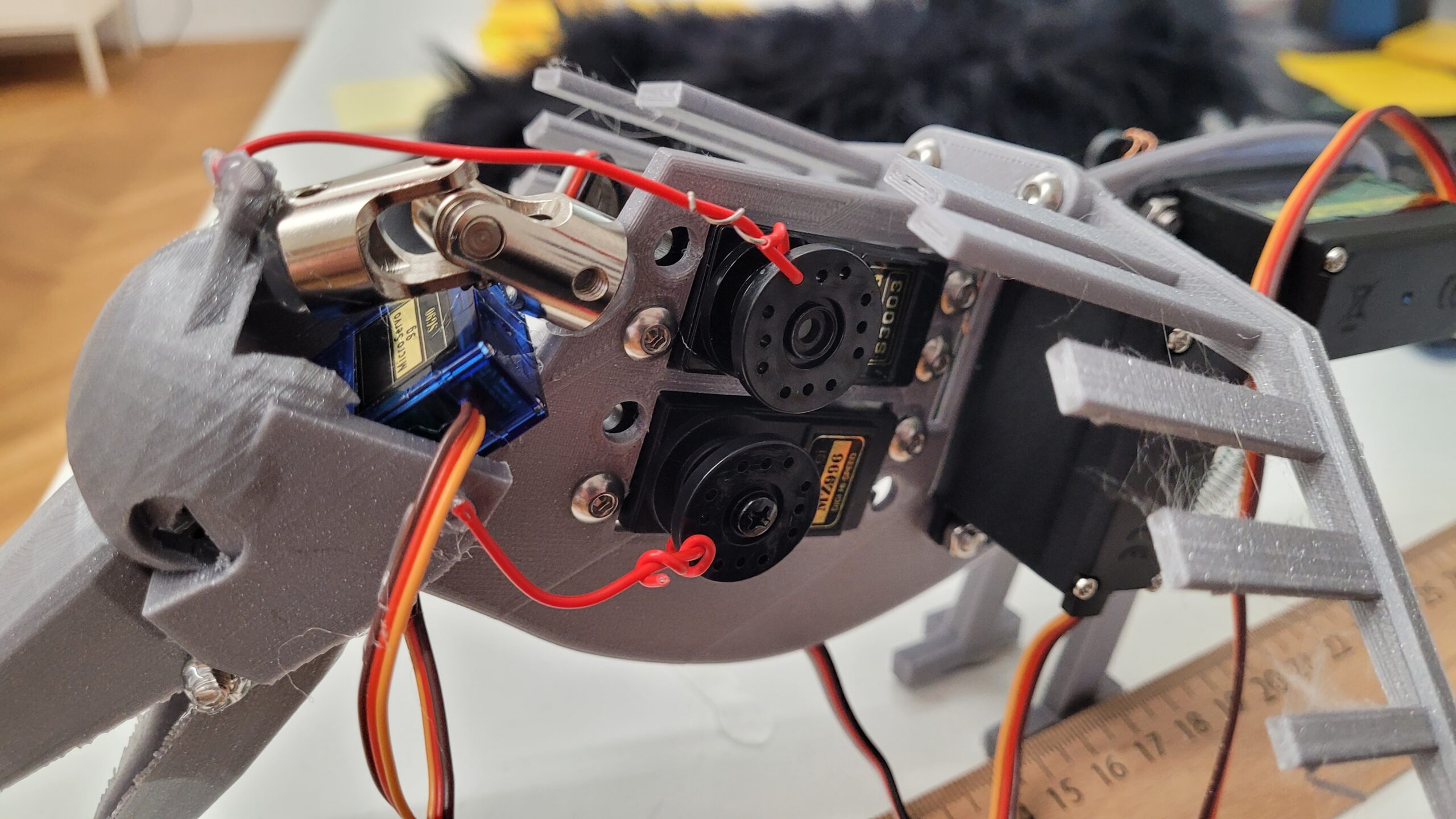 3D-printed raven head frame with exposed servos, red wires, and wiring on a workbench