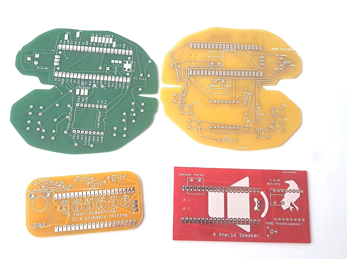 Four custom PCB boards in green, yellow, orange, and red lie on a white surface.