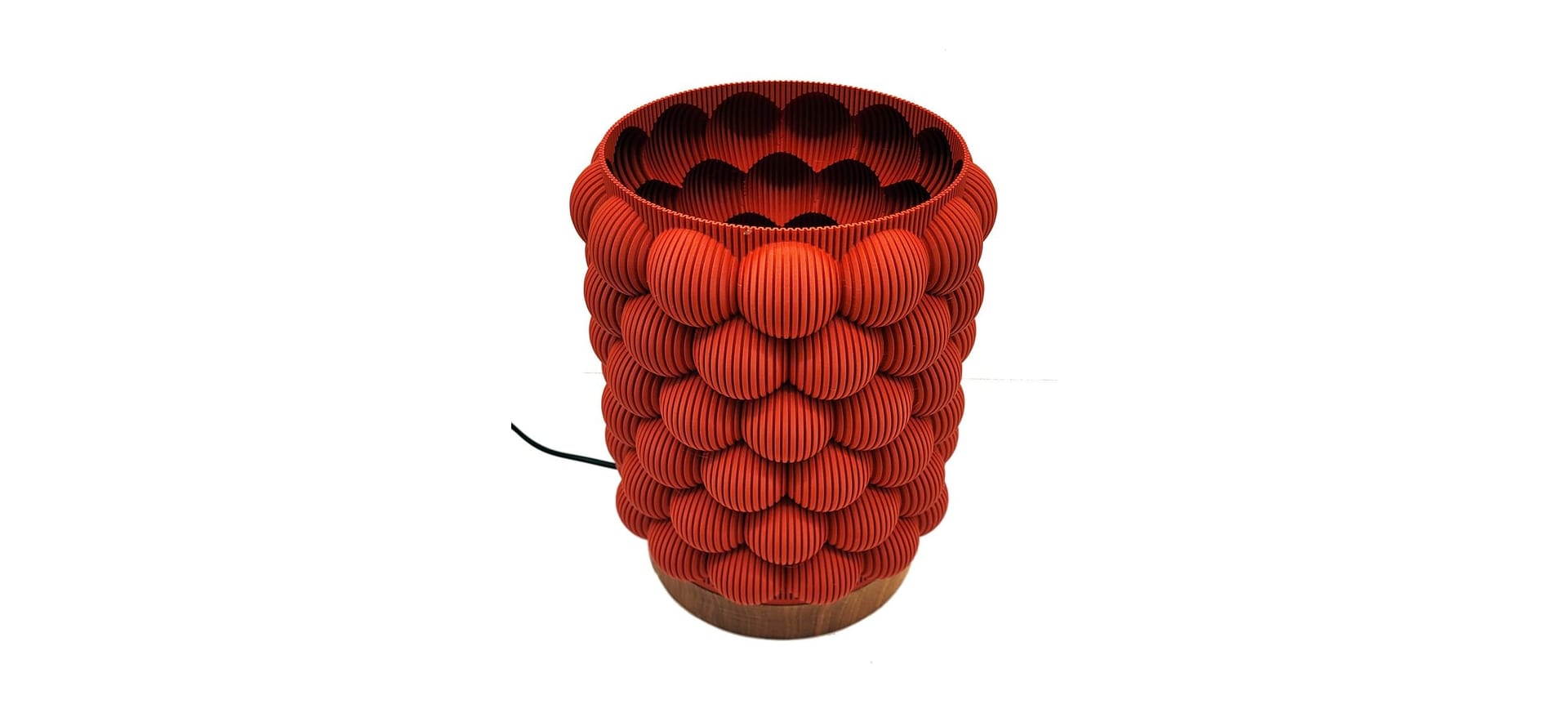 A red 3D-printed lamp covered in overlapping round ribbed scales, on a turned walnut base