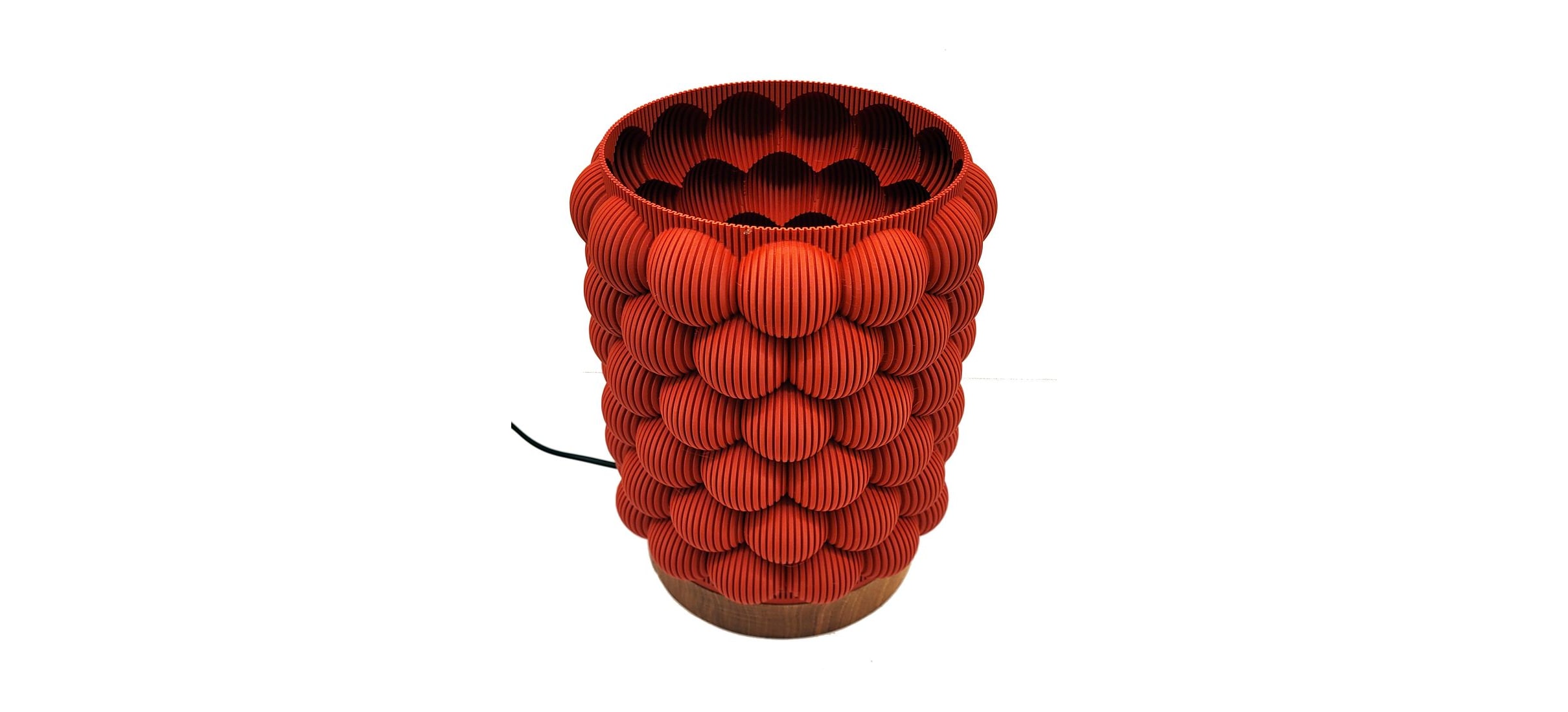 A red 3D-printed lamp covered in overlapping round ribbed scales, on a turned walnut base